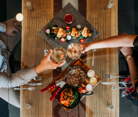 A dining table with food and 2 people cheering